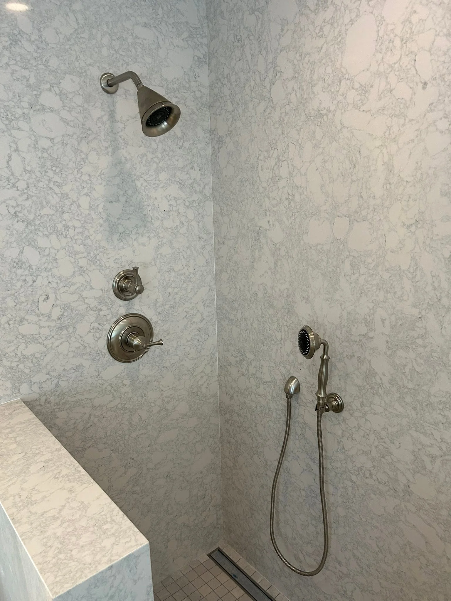 Marble shower with dual showerheads and brushed nickel fixtures